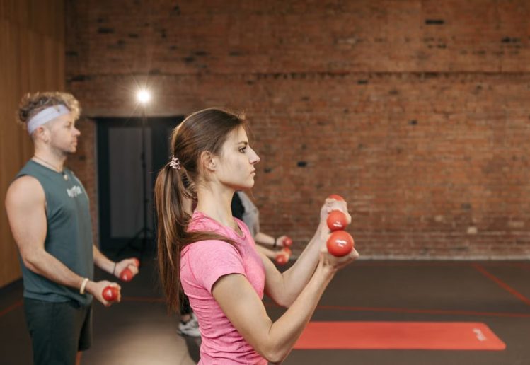Group of adults exercising indoors with dumbbells, focused on fitness and health.