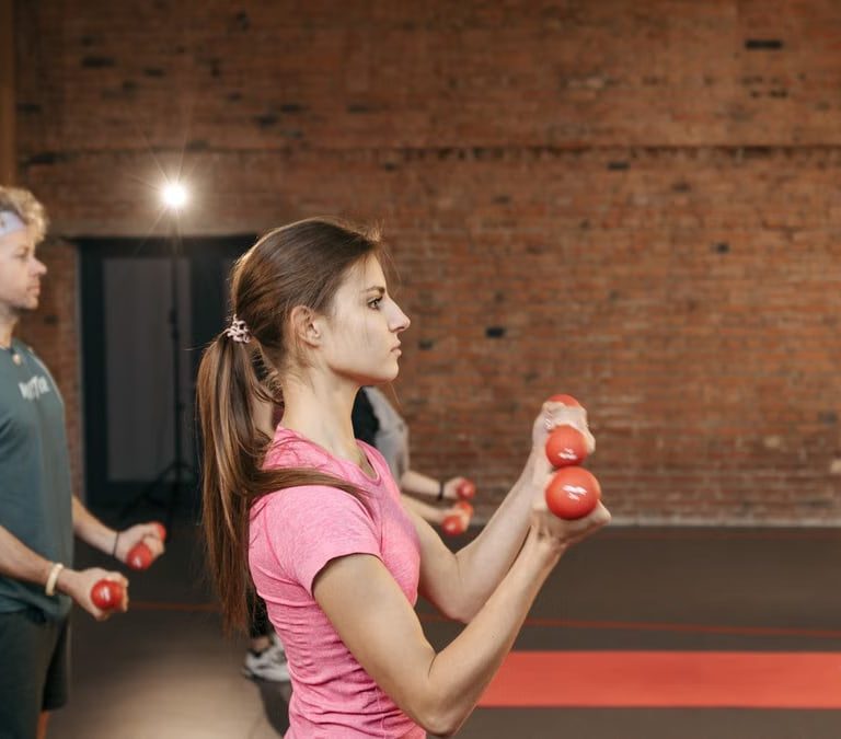 Group of adults exercising indoors with dumbbells, focused on fitness and health.