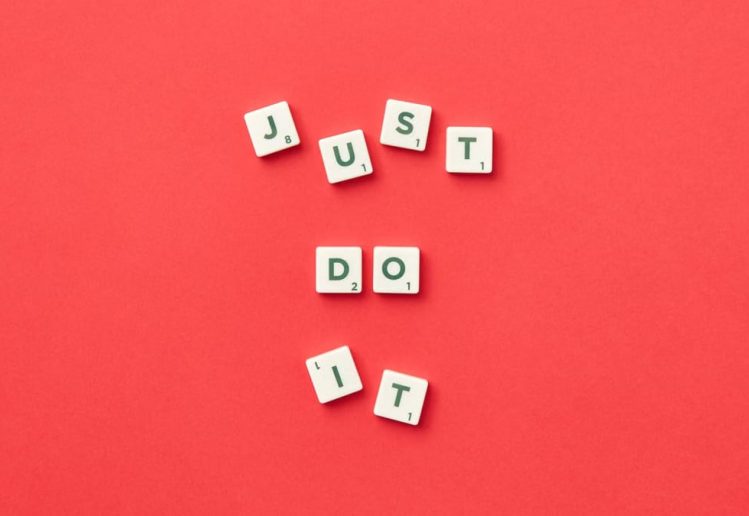 Motivational phrase 'Just Do It' spelled with Scrabble letters on a red background.