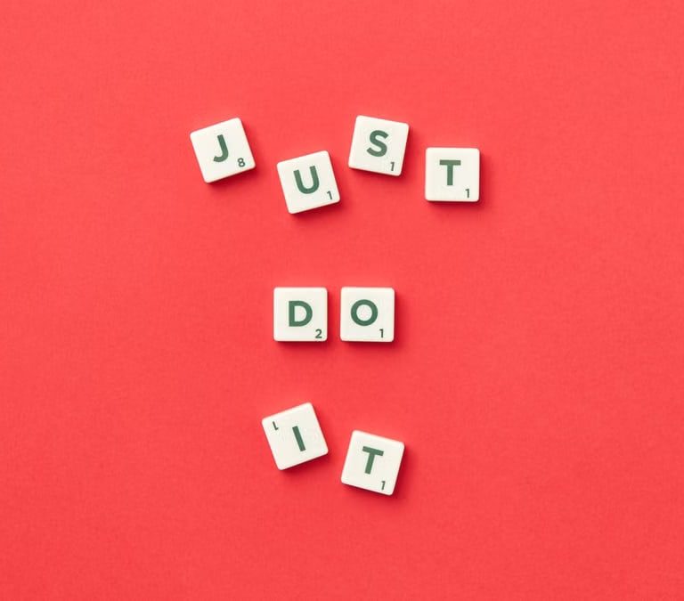 Motivational phrase 'Just Do It' spelled with Scrabble letters on a red background.