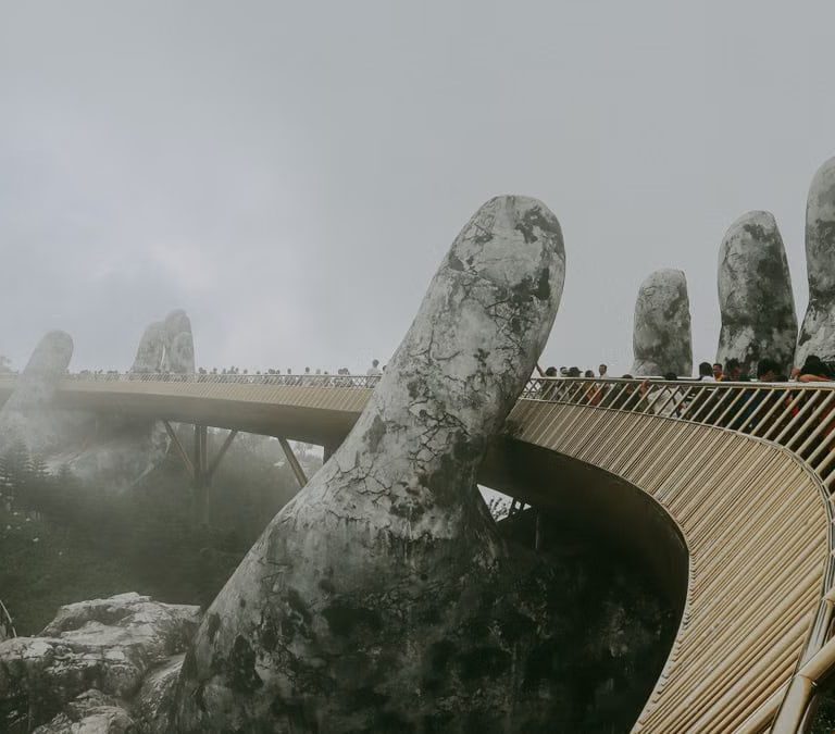 Stunning view of Golden Bridge held by stone hands enveloped in mist, Ba Na Hills.